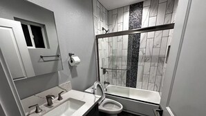 Une salle de bain moderne avec un lavabo blanc, des toilettes et une baignoire.