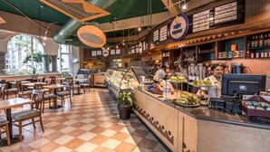 Un café avec un sol à carreaux, un comptoir où est affiché le menu, et une vue sur l’extérieur.