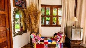 Ein Zimmer mit Holztür, einem Spiegel, einem bunten Sofa, einer Lampe und einem Heizkörper.