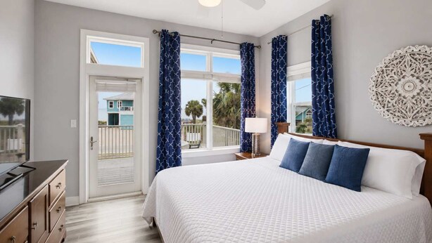 A hotel room with a bed, a television, a desk, and a window with curtains. - NEW- Salt Therapy - 5 BDR- Pool- St. George Island (Saint George Island)