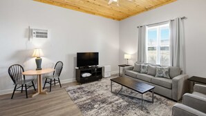 A living room with a ceiling fan, a TV, a sofa, a coffee table, and a dining area with chairs. - NEW- Salt Therapy - 5 BDR- Pool- St. George Island (Saint George Island)