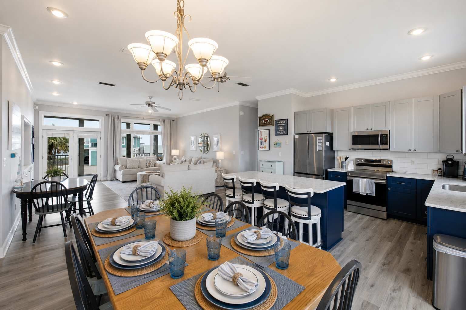 A modern kitchen with stainless steel appliances, a dining area with a wooden table set for six, and a large island with bar stools.