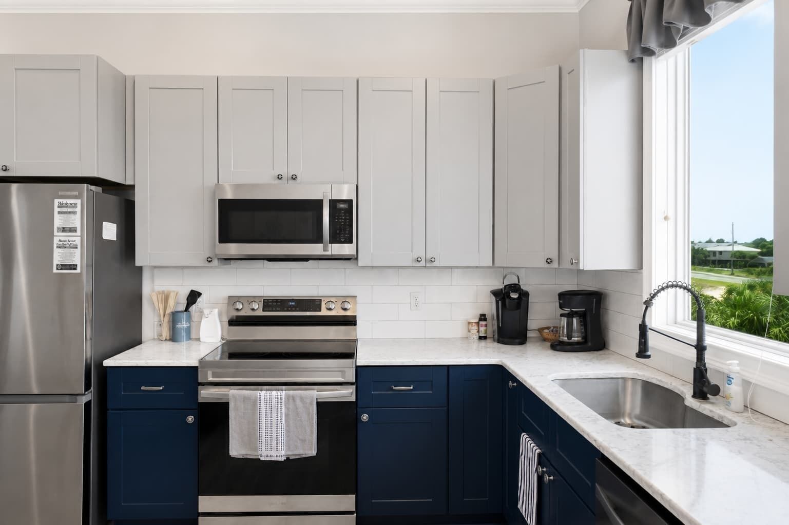 A modern kitchen with stainless steel appliances, a microwave, oven, and a sink.