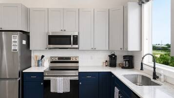 A modern kitchen with stainless steel appliances, a microwave, oven, and a sink.