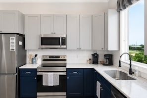 A modern kitchen with stainless steel appliances, a microwave, oven, and a sink. - NEW- Salt Therapy - 5 BDR- Pool- St. George Island (Saint George Island)