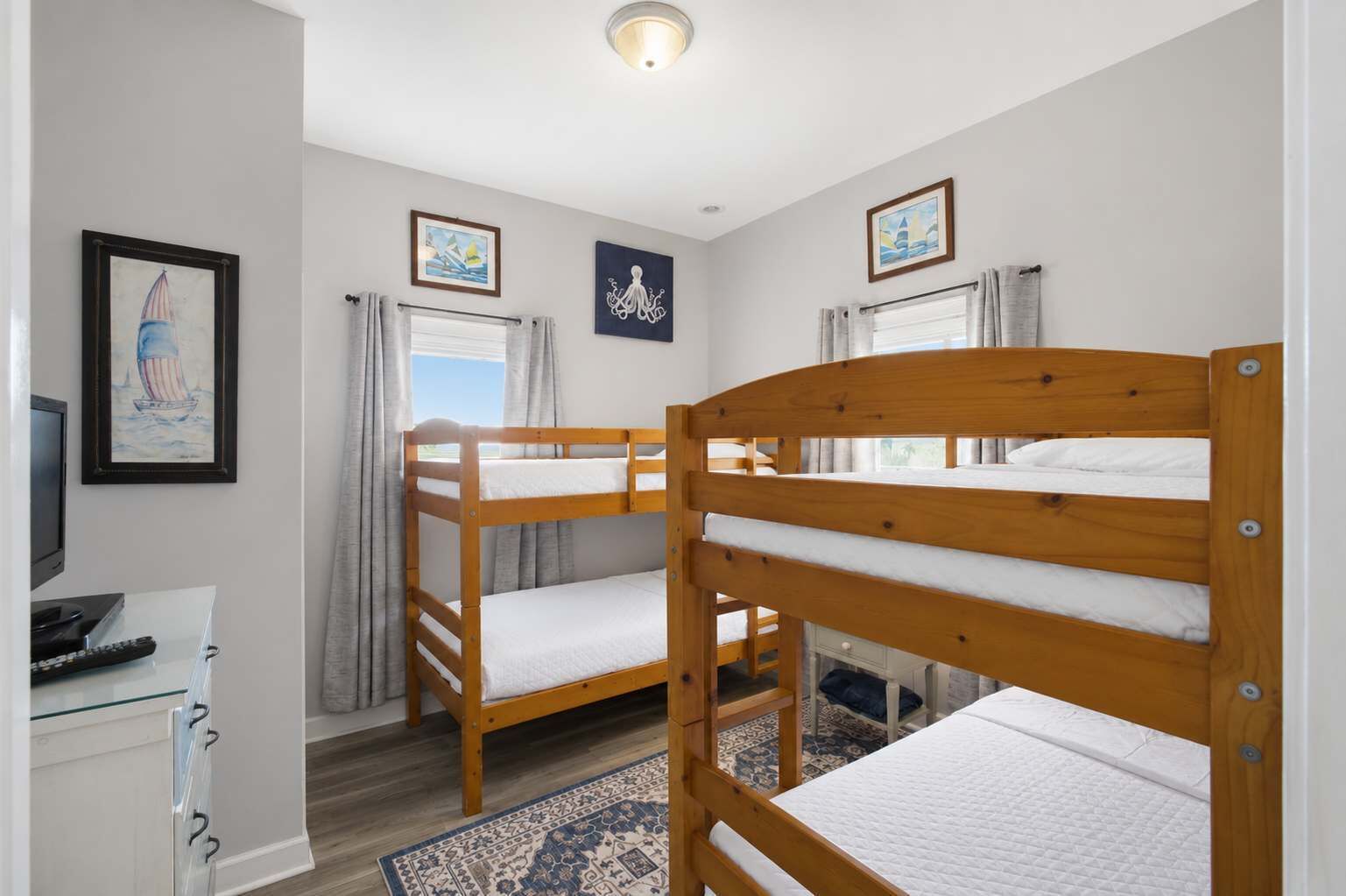 A room with bunk beds, a desk with a computer, and a window with curtains.