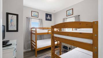 A room with bunk beds, a desk with a computer, and a window with curtains.