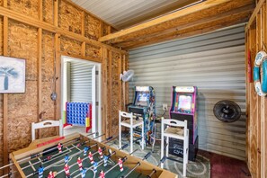A room with a foosball table, two arcade games, and a small seating area. - NEW- Salt Therapy - 5 BDR- Pool- St. George Island (Saint George Island)