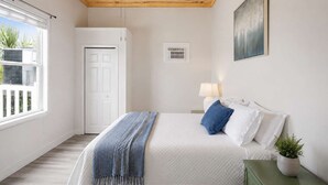 A bedroom with a bed, a nightstand, a lamp, a window, and a door. - NEW- Salt Therapy - 5 BDR- Pool- St. George Island (Saint George Island)