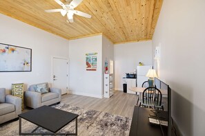 A modern living room with a ceiling fan, a sofa, a coffee table, and a dining area with a table and chairs. - NEW- Salt Therapy - 5 BDR- Pool- St. George Island (Saint George Island)