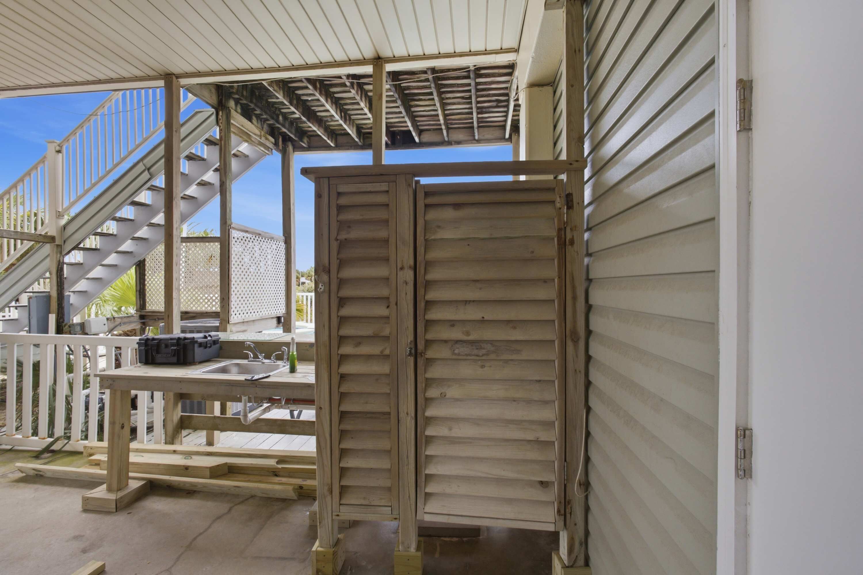 A covered outdoor area with a wooden deck, a metal staircase, and a closed wooden door.