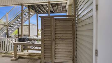A covered outdoor area with a wooden deck, a metal staircase, and a closed wooden door.