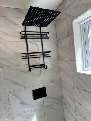 Un baño con toallero negro, cabezal de ducha y ventana.