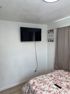 A bedroom with a bed, a mounted television, and a wall-mounted power outlet. - 3-bedroom house in welcoming Pittsburgh with cool AC breeze (Pittsburgh)