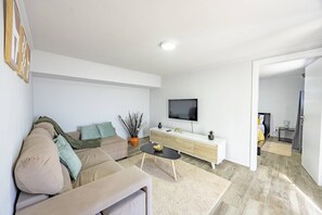 Un salon moderne avec un canapé, une table basse, un téléviseur et une console au design minimaliste.