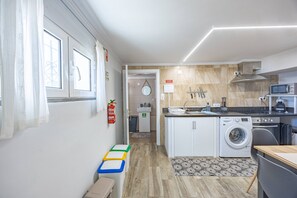 A compact kitchen with a washing machine, microwave, and a sink. - A Quintinha by Your Key Madeira (Santa Cruz)
