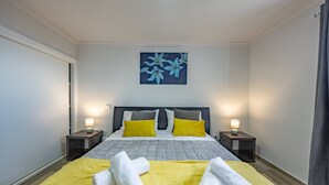 Ein Hotelzimmer mit einem Bett, zwei Nachttischen mit Lampen, einem Bild an der Wand und Handtüchern auf dem Bett.