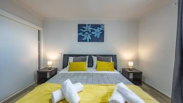 Una habitación de hotel con una cama, dos mesitas de noche con lámparas, un cuadro en la pared y toallas sobre la cama.
