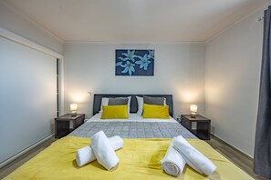 Ein Hotelzimmer mit einem Bett, zwei Nachttischen mit Lampen, einem Bild an der Wand und Handtüchern auf dem Bett.