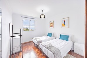 Quarto com duas camas, uma janela e um quadro na parede.