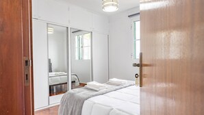 Een slaapkamer met een bed, een spiegel en een kledingkast.