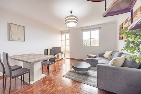 Um espaço de estar moderno com área de jantar, sofá e mesa de centro.