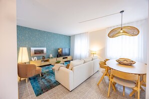 Ein modernes Wohnzimmer mit Sofa, Fernseher und Essbereich.