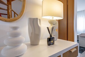 Ein weißer Konsolentisch mit einer modernen Lampe, einer dekorativen Vase und einem Schilferoherer.
