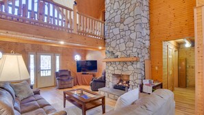 A spacious living area with a stone fireplace, wooden ceiling, and a balcony. - Wonderful 6-bedroom house with Hot Tub in charming Luray (Luray)