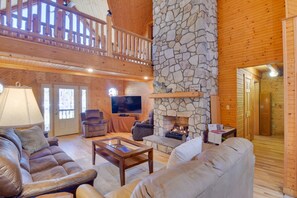 A spacious living area with a stone fireplace, wooden ceiling, and a balcony. - Wonderful 6-bedroom house with Hot Tub in charming Luray (Luray)