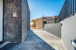 A narrow alleyway with a stone wall on one side and a concrete wall on the other, leading to a building with a red-tiled roof. - Endless Horizon by YOUR KEY (Santa Cruz)