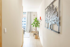 A hallway with a plant, a wall-mounted decorative panel, and a door leading to a room. - Fénix Horizon Suite by YOUR KEY (Santa Cruz)
