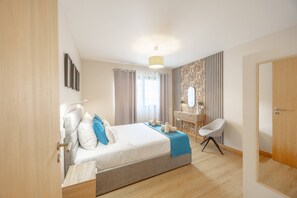 A modern hotel room with a large bed, a bedside table, a chair, and a bathroom door. - Fénix Horizon Suite by YOUR KEY (Santa Cruz)