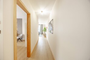 A hallway with a wooden door frame, a chair, and a wall-mounted light fixture. - Fénix Horizon Suite by YOUR KEY (Santa Cruz)