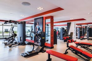 A gym with exercise equipment, benches, and motivational posters.