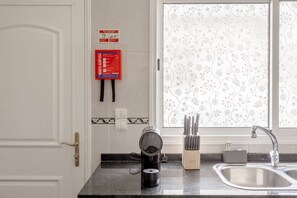 Una cocina con cafetera, bloque de cuchillos y un lavabo.