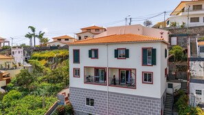 A multi-story building with a red-tiled roof, balconies, and a brick facade. - Funchal Haven by YOUR KEY (Funchal)