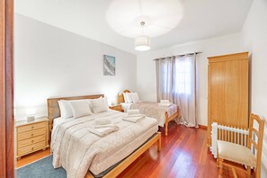 A hotel room with two beds, a wooden wardrobe, a radiator, and a chair. - L&P Countryside by YOUR KEY (Santana)