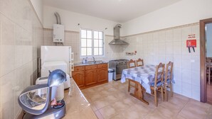 A kitchen with a stove, sink, and a dining table with chairs. - L&P Countryside by YOUR KEY (Santana)