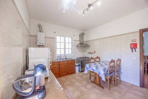 A kitchen with a stove, sink, and a dining table with chairs. - L&P Countryside by YOUR KEY (Santana)