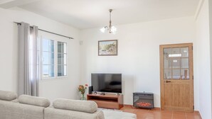 A living room with a sofa, a television, a fireplace, and a door. - L&P Countryside by YOUR KEY (Santana)
