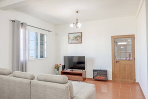 A living room with a sofa, a television, a fireplace, and a door. - L&P Countryside by YOUR KEY (Santana)