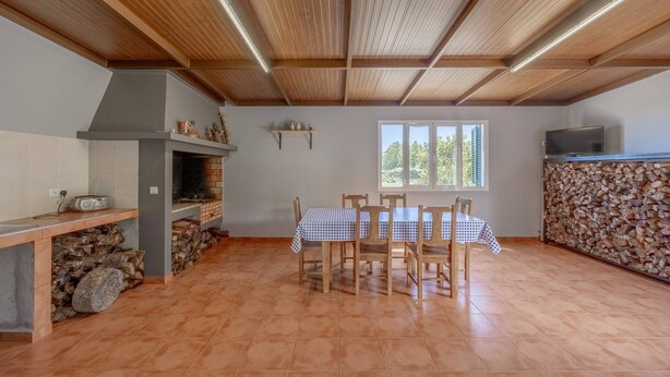 A spacious kitchen with a built-in grill, a dining table with chairs, and a large window providing a view of the outdoors. - L&P Countryside by YOUR KEY (Santana)