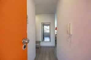 A hallway with a door leading to a room, a framed picture on the wall, and a telephone. - Lux Mare Funchal by YOUR KEY (Funchal)