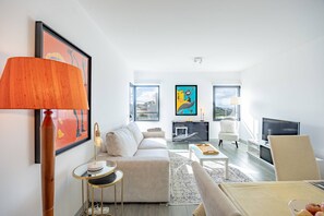 A modern living room with a sofa, a coffee table, a TV, and artwork on the walls. - Lux Mare Funchal by YOUR KEY (Funchal)