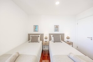 Habitación doble con dos camas, mesitas de noche, lámparas y una puerta.