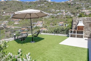 Un patio con una parrilla, dos sillas y una mesa bajo un toldo.