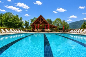 Ein Schwimmbecken mit Liegestühlen und einem Holzpavillon.