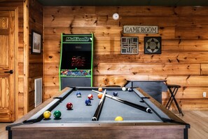 Ein Billardtisch mit Kugeln, ein Multicade-Videospiel und ein Schild mit der Aufschrift 'GAME ROOM'.
