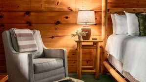 A cozy room with a wooden bed, a chair with a blanket, a small table with a lamp, and a potted plant. - VIEWS! / Hot Tub / Nintendo Switch / Games! (Sevierville)
